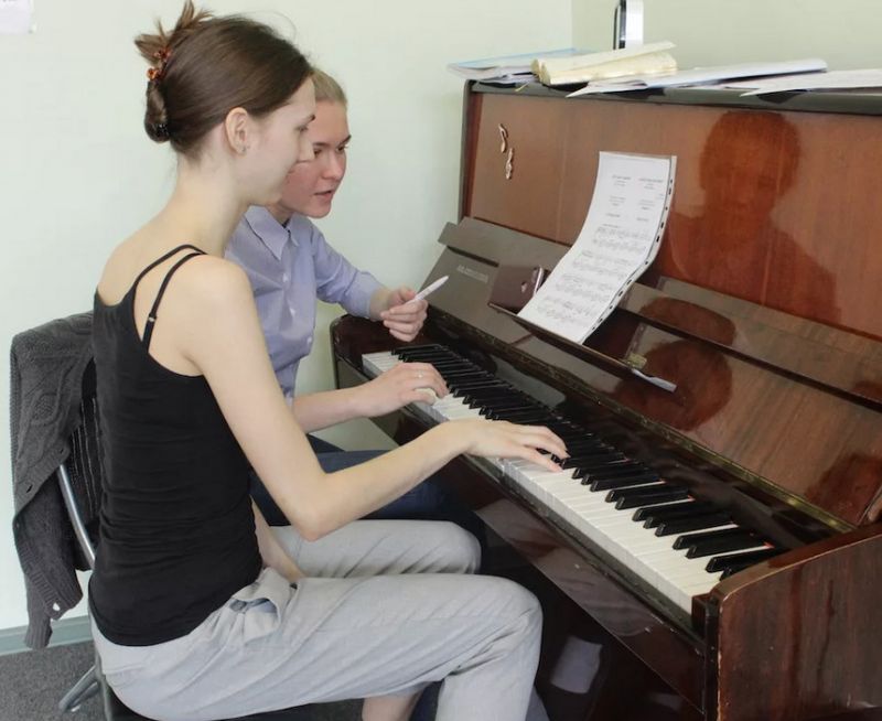 Девушка обучает девочку игре на фортопиано